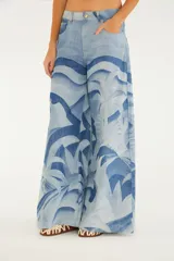 Pantalón palazzo de denim con tiro alto, piernas amplias y estampado tropical en tonos azules.