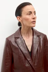 Blazer de eco cuero color chocolate con textura de cocodrilo, cuello alto y solapas.