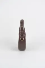 Cartera mini hobo estructurada de cuero negro, decorada con arandelas metálicas doradas en toda la superficie. Cuenta con asa corta de mano y correa de cadena metálica extraíble.