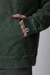 Buzo canguro de corte oversize en color verde con efecto de teñido desgastado. Cuenta con capucha, bolsillo frontal tipo canguro y puños acanalados.