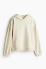Canguro oversize de color beige con capucha de doble capa, bolsillo tipo canguro frontal, hombros caídos y puños y bajo acanalados, con interior cepillado suave.