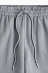 Pantalón deportivo gris de tiro alto, con cordón ajustable en la cintura elástica y bolsillos al bies. Los bajos también son elásticos y el interior es cepillado suave.