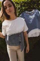 Remera blanca de algodón con intervención de denim en la parte inferior, con botones y ruedo irregular con flecos.