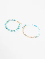Set de dos pulseras doradas: una con piedras turquesas irregulares y otra con strass engarzados, ajustable con cordón celeste.