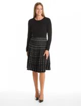 Vestido midi de punto con cuerpo liso negro de manga larga y falda acampanada con patrón geométrico vertical en contraste. Presenta escote redondo a la base y diseño entallado.