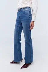 Jean acampanado de tiro medio, color azul denim, con detalle de flor bordada en el bolsillo trasero.