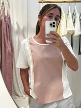 Remera de diseño combinado en algodón y lino, con panel frontal y posterior en color amarillo suave y laterales en blanco. Presenta detalles de puntilla vertical en la unión de los paneles, cuello redondo y un corte asimétrico con el ruedo trasero ligeramente más largo.