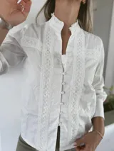 Camisa negra con cuello alto, mangas largas abullonadas y cierre frontal con botones. Presenta detalles de encaje y lentejuelas en el frente.