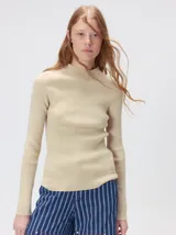 Remera de cuello alto tipo polera, confeccionada en tela rib con textura acanalada y ajuste al cuerpo. Presenta mangas largas y un pequeño bordado distintivo en la parte inferior.