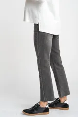 Pantalón de jeans gris oscuro, de corte flare y tiro medio, con ruedo desflecado.