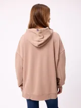 Canguro oversize de color gris con efecto lavado, capucha con cordones ajustables, bolsillo frontal tipo canguro y parche pequeño con logo de la marca en el pecho.