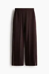 Pantalón sastrero de tejido efecto neopreno color marrón oscuro, de corte recto con raya central pespuntada y franja lateral en color rosado contrastante. Cuenta con bolsillos al bies y cierre frontal con botón oculto y corchete.