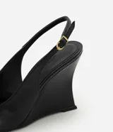 Zapato tipo slingback de color negro con acabado liso. Presenta punta fina, tira trasera ajustable con hebilla metálica y un diseño de taco anabela integrado a la suela.