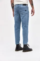 Jean de corte mom fit en color azul medio con acabado marmolado, confeccionado en denim resistente. Presenta cierre frontal con botón, bolsillos laterales y traseros, y un ajuste ligeramente holgado en las piernas con terminación recta.