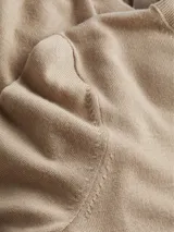 Sweater color beige de tejido de punto, con cuello alto y mangas largas.