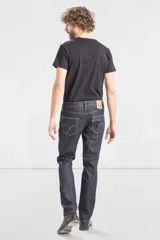 Jean de corte slim fit, color azul oscuro con costuras en contraste. Presenta diseño de cinco bolsillos, cierre frontal con cremallera y botón metálico.