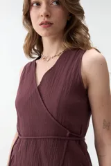 Chaleco cruzado negro sin mangas con escote en V y lazo de ajuste lateral, confeccionado en tejido texturado.