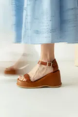 Sandalias negras de cuero sintético con plataforma y taco de cuña. Tienen dos tiras en el empeine y una tira con hebilla alrededor del tobillo.