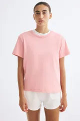 Remera oversized de algodón suave, color rosado, con cuello redondo ribeteado y mangas cortas con hombros levemente caídos.