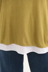 Sweater de tejido de punto color mostaza con diseño superpuesto, escote en V, mangas largas y detalle de vivo plateado en el borde de las mangas y el ruedo.