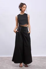 Pantalón negro de corte palazzo con pespuntes blancos decorativos en la cintura y los laterales. Tiene bolsillos laterales y cierre frontal.