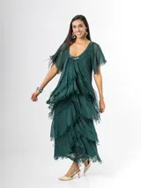 Vestido largo de seda italiana color verde oscuro, con capas escalonadas con flecos, escote en V con detalle de paillettes y mangas cortas fluidas.