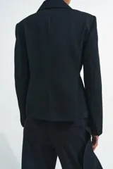 Blazer entallada de Zara, confeccionada en hilatura con lana. Presenta cuello solapa de muescas, manga larga con botones en puños, bolsillos de vivo en el delantero y cierre frontal cruzado con botones.