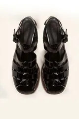 Sandalia plateada de cuero con tiras entrecruzadas, taco de madera y hebilla lateral.