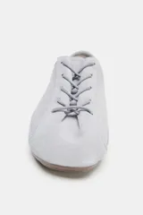 Zapato tipo blucher de estilo deportivo confeccionado en piel, con cierre de cordones, tirador trasero y suela plana.