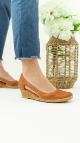 Zapato de cuero negro con taco corrido revestido en corcho y plataforma de yute trenzado. Cuenta con diseño lateral abierto y puntera redondeada.