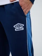Pantalón de jogging azul marino Umbro del Club Nacional de Football, con cordón ajustable en la cintura, puños elastizados en los tobillos y bandas laterales en tonos de azul. Cuenta con el escudo del club en una pierna y el logo de la marca en la otra.