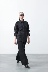 Jean wide leg de color negro con silueta amplia y caída fluida. Presenta detalles de tachas aplicadas que recorren el diseño en forma de ondas. Confeccionado en denim de algodón.
