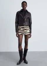 Falda corta de tiro medio con estampado animal print de cebra. Presenta un diseño recto y cierre de cremallera lateral.