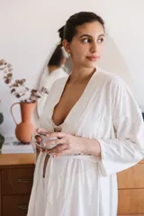 Bata maternal de algodón en color blanco, con diseño cruzado, mangas largas y lazo ajustable en la cintura.