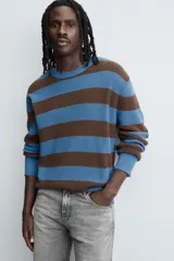 Jersey de punto de algodón con ajuste relajado, cuello redondo y manga larga. Presenta un diseño de rayas horizontales en azul y marrón, con detalles de efecto desgastado y roturas en el cuello, puños y bajo.