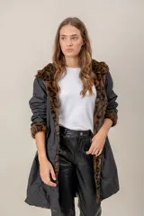 Tapado reversible de corte recto con capucha. Un lado presenta un acabado de piel sintética negra de pelo corto, mientras que el otro lado es de tela técnica lisa en color gris oscuro. Cuenta con cierre frontal y mangas largas.