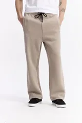 Pantalón de algodón de corte recto y estilo relajado, color beige. Cuenta con cintura elástica con cordón de ajuste, bolsillos laterales y logo de la marca estampado discretamente en el frente.