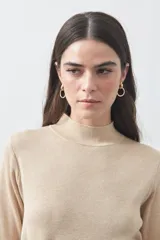 Polera de tejido de punto color beige, con cuello alto, manga larga y detalle de lazo ajustable en la cintura que aporta estructura a la silueta.