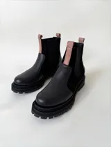 Botas tipo chelsea de cuero negro con suela track, paneles laterales elásticos y tiradores en color nude.