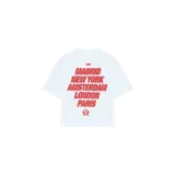 Remera oversize blanca de manga corta con estampa frontal en color rojo que incluye nombres de ciudades y un logotipo circular.