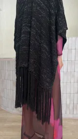 Ruana de tejido de punto color crema con diseño de líneas horizontales caladas y terminación con flecos en el ruedo.