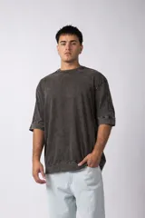 Remera de corte oversize con efecto de lavado gastado, confeccionada en algodón pesado. Presenta cuello redondo, mangas cortas con costuras visibles y un diseño amplio.