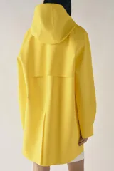 Cazadora impermeable de acabado engomado en color amarillo, con capucha ajustable, cierre frontal con botones a presión, bolsillos laterales y mangas largas ajustables.