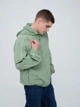 Campera rompevientos Umbro modelo Venti, de color negro con líneas blancas en las mangas y hombros, capucha con cordón de ajuste y cierre frontal completo. Cuenta con el logo de la marca bordado en el pecho.