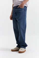Jean de corte baggy con tiro medio, diseño amplio y holgado en piernas y cadera, con pasacintos y cierre frontal.