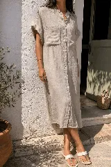 Vestido camisero largo de lino, con cuello mao, mangas cortas con vuelta y bolsillos frontales con solapa. Presenta cierre frontal con botonadura completa.