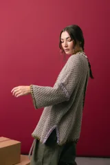 Saco oversize de tejido de punto en color beige, con mangas caídas y detalles de bordado a mano en tonos verde y lila en los bordes y costuras.