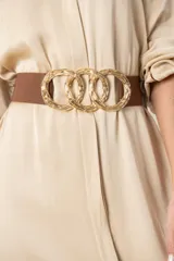 Cinto marrón elástico con hebilla dorada formada por tres aros entrelazados.