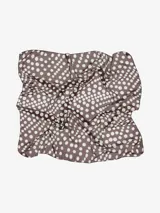 Pañuelo cuadrado de tela liviana con estampado multicolor en tonos marrones, blancos y naranjas con patrones geométricos y abstractos.