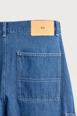 Jeans loose fit de tiro medio, confeccionados en denim de algodón color azul con efecto lavado. Presentan diseño de cinco bolsillos, bolsillo plastrón estilo carpintero en la pierna y cierre frontal con cremallera y botón.